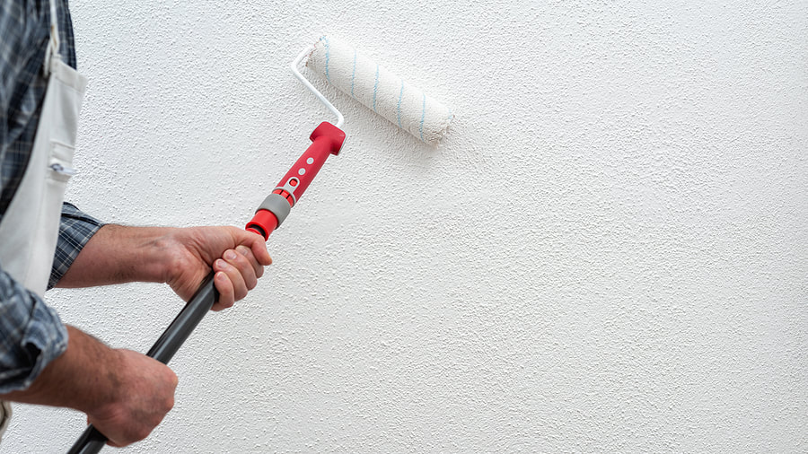 someone painting the wall using roller brush